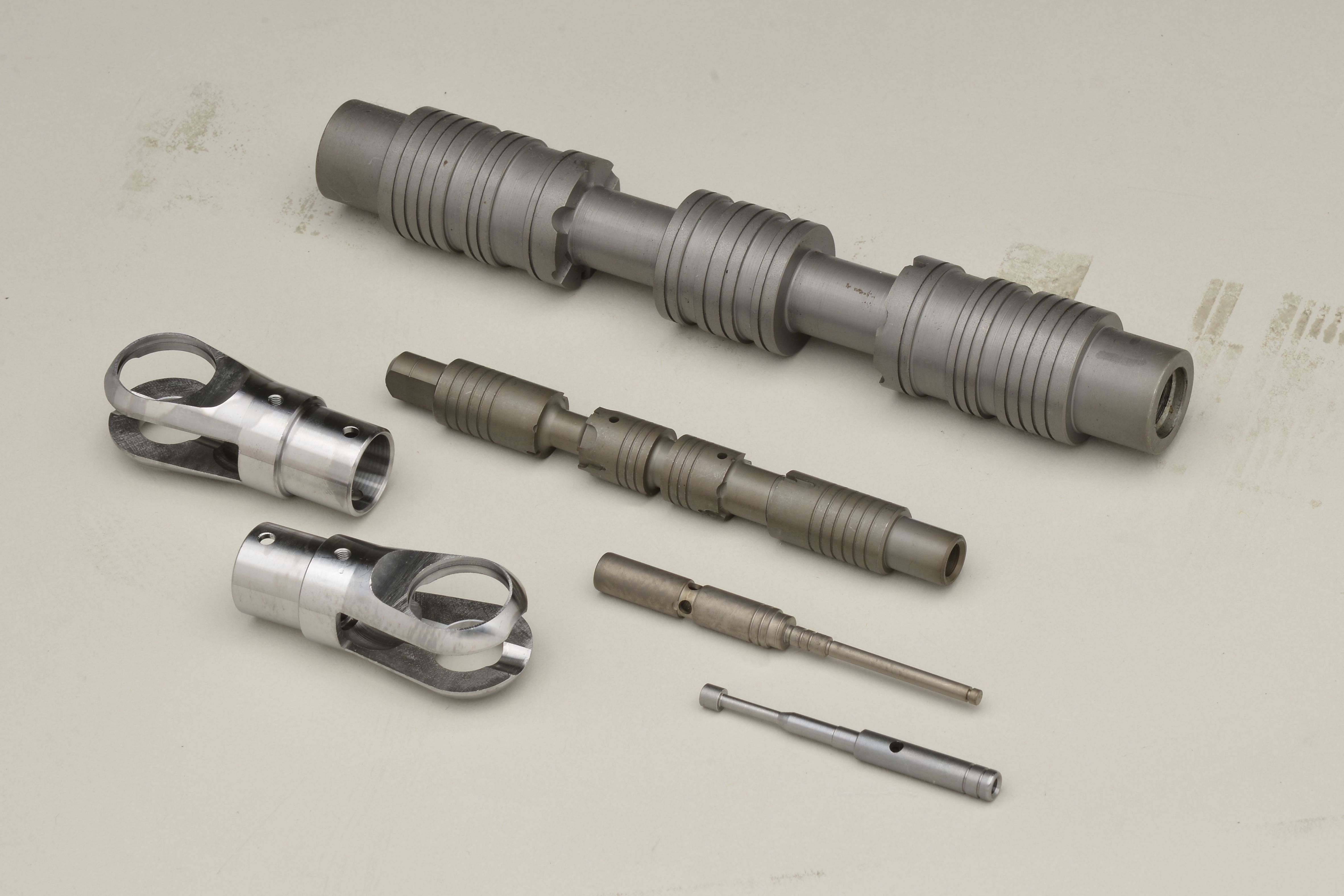 ガス浸炭による熱処理加工を施された各種金属部品。シャフトやローラーなど様々なサイズの部品が並ぶ。表面硬化処理により強度と耐摩耗性を向上