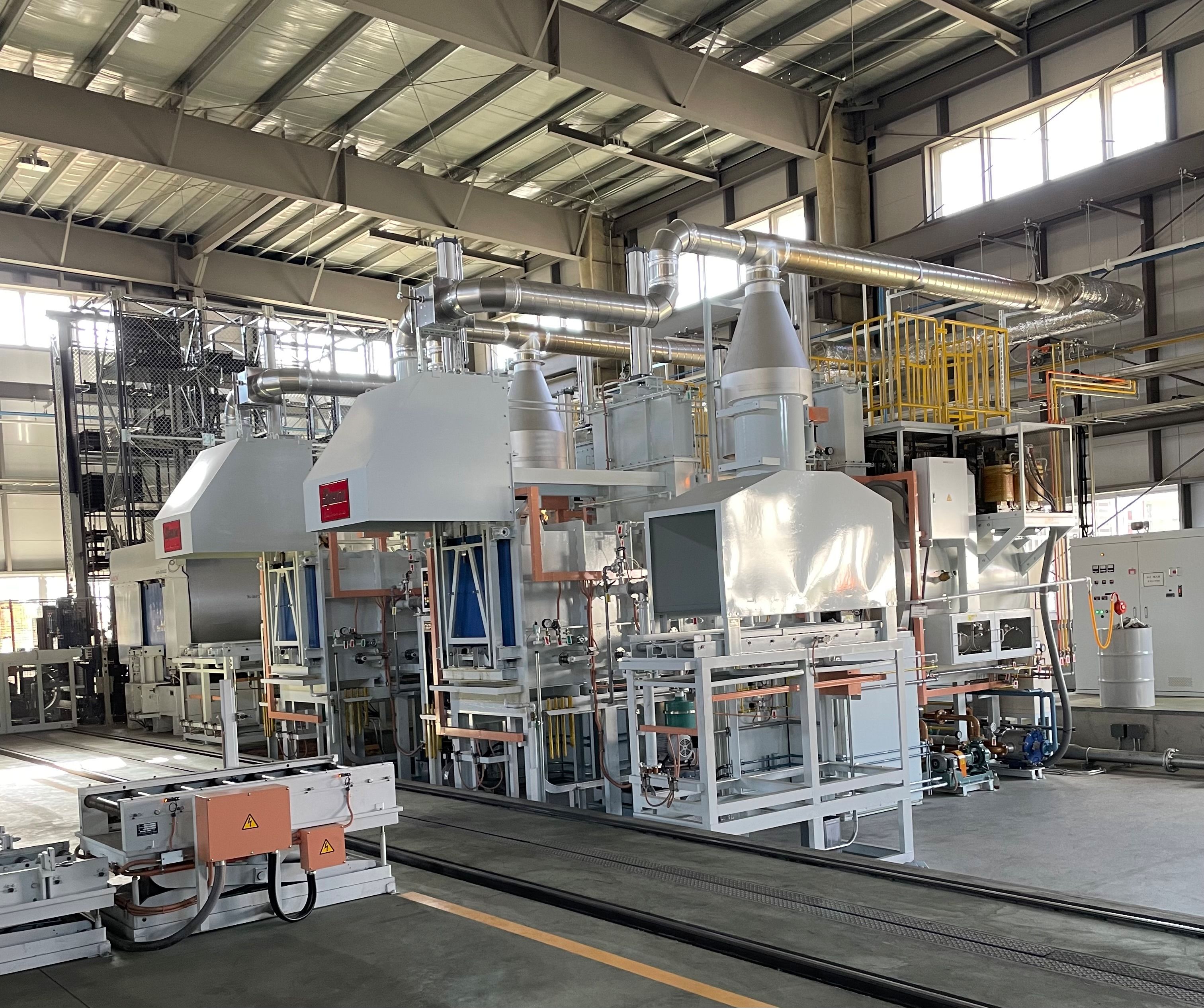 新工場内に設置された多品種少量生産対応の大型熱処理炉。高い天井の工場内に配置された白色の産業用設備